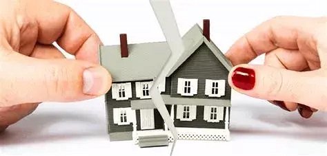 Two hands are cutting a paper model of a house for true default uncontested divorce $695 divorce attorney